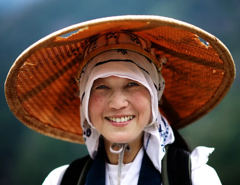 Pellegrina sorridente con un ampio cappello di paglia sul Kumano Kodo.