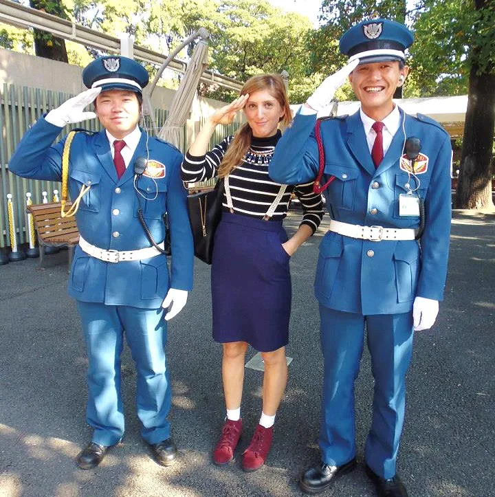 Una persona in posa tra due guardie in uniforme blu.