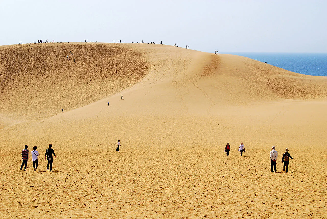 Visitatori sulle dune di sabbia di Tottori, con il mare sullo sfondo.
